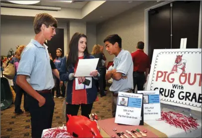  ?? The Sentinel-Record/Mara Kuhn ?? FUNDRAISER: Nathan Ahlers, 15, left, and Ian Hollis, 15, help Scarlet Gooch, 17, during the silent auction for the sixth annual Tailgate Fundraiser for Our Promise Cancer Resources at The Hotel Hot Springs &amp; Spa on Saturday.