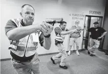  ?? Tony Gutierrez / Associated Press ?? Police officers David Riggall, left, and Nick Guadarrama show Stephen Hatherley, second from right, and Chris Scott how to clear a hallway intersecti­on during a security training in Haslet.