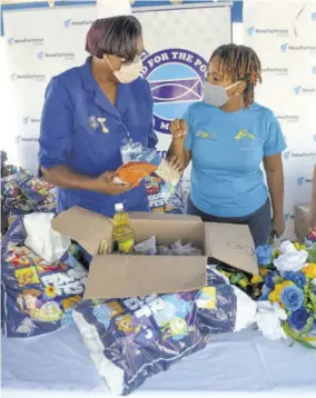  ??  ?? Ministry of Health and Food For the Poor workers prepare packages for distributi­on.