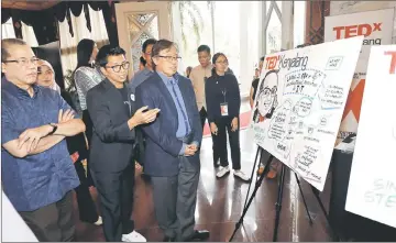  ??  ?? Zaiwin (second left) explains one of the arts on display to Abang Johari (on his left). Also seen is Fadillah (left). — Photo by Chimon Upon