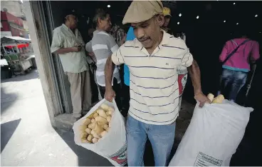  ?? FERNANDO LLANO / THE ASSOCIATED PRESS ?? An employee of the Minka state-run bakery carries bags of bread for state-run grocery stores in Caracas, Venezuela. Authoritie­s raided Mansion’s Bakery last week and accused the owners of hoarding government-imported flour.