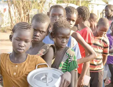  ??  ?? South Sudanese children wait in line for turns to get food.