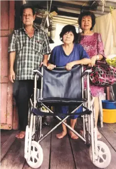  ??  ?? Lim (left) hands over the wheelchair to Salamah, as Lim’s friend known only as Tang looks on.