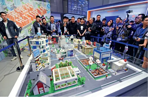  ??  ?? Le 7 mai 2019, lors de la 2e Exposition sur les réalisatio­ns de la constructi­on numérique en Chine, les visiteurs observent une maquette d’une « ville intelligen­te ».