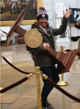  ?? GEtty IMaGEs FILE pHotos ?? NOT SO HAPPY NOW: Adam Johnson, seen carrying House Speaker Nancy Pelosi’s lectern through the Rotunda of the U.S. Capitol after a pro-Trump mob stormed the building on Wednesday, faces charges including theft of government property. At left, supporters of President Trump are seen inside the Capitol.