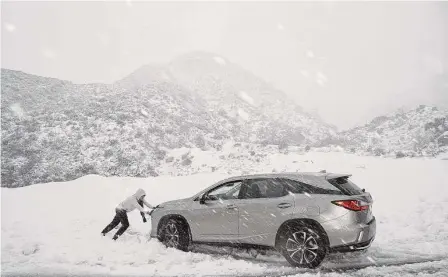  ?? Eric Thayer/Bloomberg ?? A car is stuck Friday in the San Gabriel Mountains during a storm in La Canada, Calif. A sprawling winter storm is sweeping across the northern U.S. this week, unleashing bitter cold from California to Maine even as the Southeast sees record warmth.