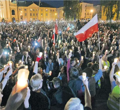  ??  ?? Demonstran­ten vor dem Obersten Gericht in Warschau zündeten Kerzen an und schwenkten polnische Fahnen. „Hände weg von der Justiz“, lautet ihre Botschaft.