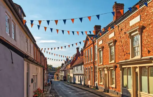  ??  ?? Bunting decorates the neat, narrow High Street at Little Walsingham, with its attractive buildings.