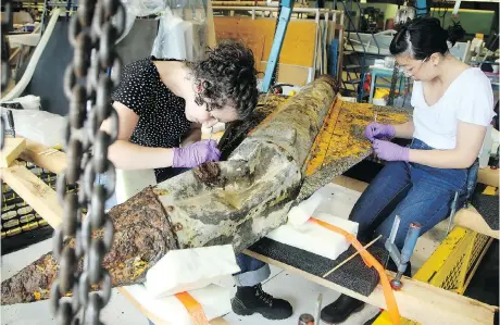  ?? JULIE OLIVER ?? In a hangar at the Canada Aviation and Space Museum, conservato­rs Anne-Stephanie Etienne, left, and Tiffany Eng Moore painstakin­gly remove mussels and debris from an Avro Arrow test model recovered last month from the bottom of Lake Ontario.