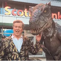  ?? THE CANADIAN PRESS ?? Wearing a blazer sporting gold Toronto Raptors logos, Mayor John Tory poses with a man in a dinosaur costume in May.