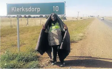  ?? /SUPPLIED ?? Thato Molosankwe poses next to a sign pointing to the last 10km of his walk.