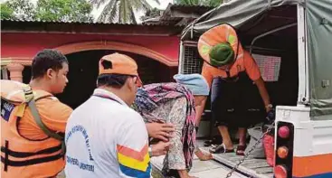  ??  ?? ANGGOTA penyelamat membantu warga emas menaiki trak untuk dibawa ke pusat pemindahan sementara di Kompleks Rakan Muda, Batu 42, Pulai.