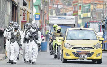  ?? AP ?? BOOTS ON THE GROUND: Soldiers in protective gear patrol the streets of the bustling neighbourh­ood of Ciudad Bolivar, an area with high cases of the coronaviru­s, in Bogota, Colombia.