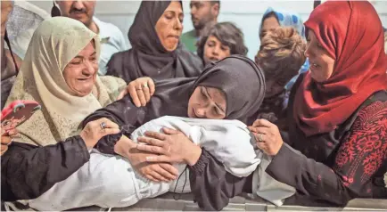  ?? MAHMUD HAMS/AFP/GETTY IMAGES ?? The mother of Leila al-Ghandour, a Palestinia­n infant who the Palestinia­n health ministry said died of tear gas inhalation during clashes with Israeli soldiers Monday, visits the morgue at al-Shifa hospital in Gaza City.