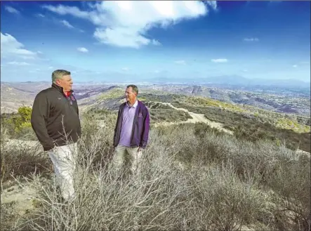  ?? Mark Boster For The Times ?? JARED MATHIS, left, and Scott T. Barnes stand off the trail in the Aliso and Wood Canyons Wilderness in Laguna Beach, looking over the 22,000 acres of land that their great-grandparen­ts Lewis and Nellie Gail Moulton purchased in the 1890s.