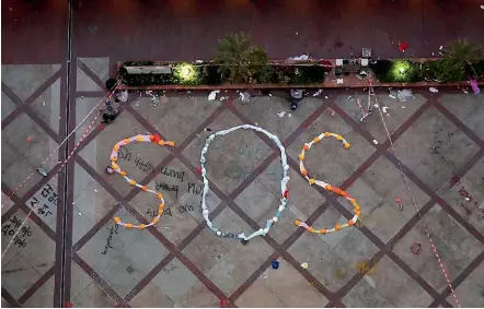  ?? AP ?? An ‘‘SOS’’ sign formed with clothes and helmets by protesters is seen inside the Hong Kong Polytechni­c University campus in Hong Kong on Friday. Six masked protesters surrendere­d early on Friday morning, bringing to about 30 the number that have come out in the past day from the university campus surrounded by police.