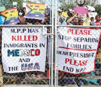  ?? DENISE CATHEY/THE BROWNSVILL­E HERALD VIA AP ?? People press signs against a closed gate to the migrant encampment, asking then President Donald Trump to end the Migrant Protection Protocols during a rally at the encampment in Oct. 2020 in Matamoros, Tamaulipas, Mexico.