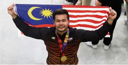  ??  ?? Special one: mohd Irfan posing with the malaysian flag after winning the discus gold with his first attempt.