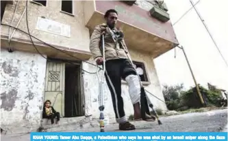  ??  ?? KHAN YOUNIS: Tamer Abu Daqqa, a Palestinia­n who says he was shot by an Israeli sniper along the Gaza border during a protest, walks with crutches outside his home. —AFP