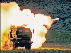  ?? ?? In this file photo, a launch truck fires the High Mobility Artillery Rocket System (Himars) produced by Lockheed Martin during combat training in the high desert of the Yakima Training Centre, Washington while a woman collects belongings in the ruble of their house after a strike destroyed three houses in the city of Slovyansk in the eastern Ukrainian region of Donbas on Wednesday.