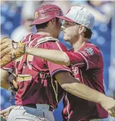  ?? AP PHoto ?? NOT DONE YET: Drew Carlton hugs catcher Jackson Lueck after closing out Florida State’s victory against Cal State Fullerton in the College World Series.