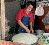  ??  ?? A man makes a crepe on a Shanghai side street.