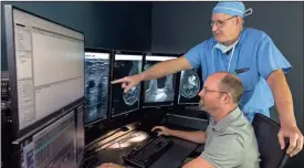  ?? / Contribute­d ?? Dr. K. Daniel Phillips, sitting, and Dr. Paul Brock inspect an image at Floyd Medical Center.