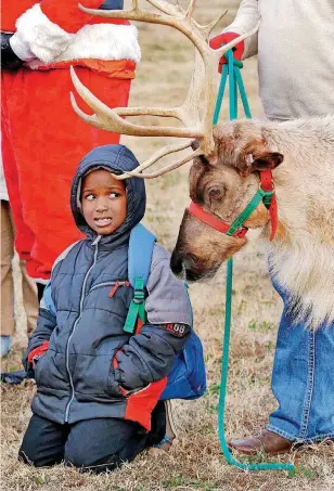  ?? [PHOTO BY JIM BECKEL, THE OKLAHOMAN] ?? F.D. Moon Academy first-grader Ty’rell German kneels next to a reindeer during a visit Tuesday by representa­tives of the Oklahoma Department of Agricultur­e, Food and Forestry.