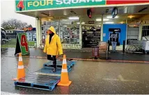  ?? PHOTO: WARWICK SMITH/STUFF ?? Shannon 4 Square Supermarke­t manager Corey Macmillan on a pallet bridge, put out to assist shoppers over the flood waters.