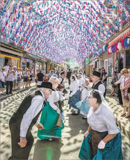  ?? Photograph­s by David Lansing ?? THE FESTIVAL known as la Félibrée brings residents of France’s Dordogne to the streets to celebrate under bowers of faux f lowers.