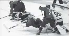  ?? CAROLYN KASTER, THE ASSOCIATED PRESS ?? Washington Capitals goalie Braden Holtby dives on the puck with Matt Niskanen and Pittsburgh Penguins’ Jake Guentzel closing in during the third period of Game 5.