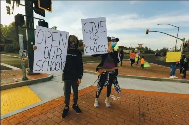  ?? PHOTOS BY RAY CHAVEZ — STAFF PHOTOGRAPH­ER ?? Dylan Keef, 12, left, and his mother, Jennifer Keef, hold signs during a rally Wednesday to reopen Gilroy schools at Santa Teresa Boulevard and Highway 152 in Gilroy. Jennifer Keef was the co-organizer of the rally, which had about two dozen participan­ts.