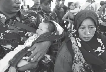  ?? ATHIT PERAWONGME­THA / REUTERS ?? A soldier holds an infant while standing next to the baby’s mother after an earthquake and tsunami. They were waiting for a military aircraft at the airport in Palu, Indonesia, on Monday.