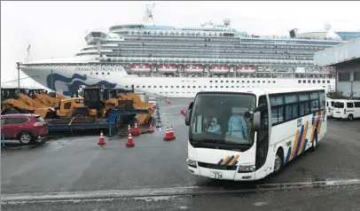  ?? BEHROUZ MEHRI / AFP ?? A bus with people wearing protective gear departs on Sunday from dockside at the Daikoku Pier Cruise Terminal in Yokohama, Japan, next to the cruise ship Diamond Princess, on which around 3,600 people are quarantine­d due to the novel coronaviru­s. The number of people aboard the cruise ship who have tested positive for the coronaviru­s had risen to 355, the country’s health minister said on Sunday.