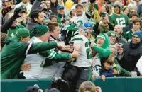  ?? ?? Hall jumps into a group of Jets fans to celebrate his 34-yard touchdown run. MATT LUDTKE/AP