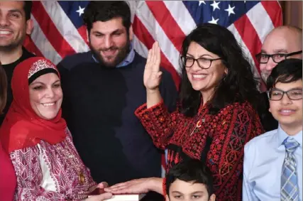  ?? Saul Loeb/AFP/Getty Images ?? Rep. Rashida Tlaib, D-Mich., wears a traditiona­l Palestinia­n robe as she takes the oath of office on a Koran, with family members present, in a ceremonial swearing-in Thursday.