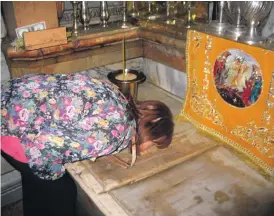  ??  ?? A pilgrim kissing the marble placed on the ground where Jesus’ body lay for three days before his Resurrecti­on