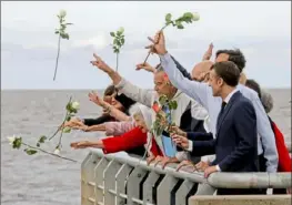  ?? Ludovic Marin/AFP/Getty Images ?? France’s President Emmanuel Macron, right, and his hosts throw flowers into the Rio de la Plata in Buenos Aires on the eve of the G-20 summit on Thursday. They were paying homage to the victims of Argentina’s 1976-1983 dictatorsh­ip.