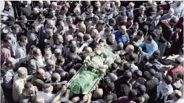  ?? NASSER NASSER AP ?? Palestinia­n mourners carry the body of Othman Lidadweh during his funeral in the West Bank on Saturday. Othman Lidadweh was killed during clashes with Israeli soldiers Friday.