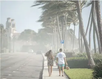  ??  ?? Sea spray, sand and winds sweep across South Ocean Boulevard in Palm Beach, Florida, as Palm Beach County readies for Hurricane Isaias on Saturday.