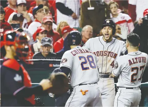  ?? ROB CARR/GETTY IMAGES ?? Robinson Chirinos of the Houston Astros is congratula­ted by teammates George Springer and Jose Altuve after hitting a solo home run against the Washington Nationals in Game 3 of the World Series on Friday. The Astros won 4-1 to cut Washington’s series lead in half.