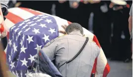  ?? [PHOTO BY PATRICK DENNIS/BATON ROUGE ADVOCATE VIA AP] ?? A member of Baton Rouge police Cpl. Montrell Jackson’s unit kneels and touches his casket during his funeral Monday at the Living Faith Christian Center in Baton Rouge, La. Jackson and multiple police officers were killed and wounded July 17, in a...