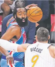  ?? MARY ALTAFFER/ASSOCIATED PRESS ?? Nets guard James Harden is guarded by Magic center Nikola Vucevic on Saturday in New York. Harden scored 32 points in his debut.