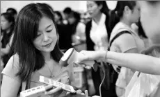  ?? XINHUA ?? A woman uses Alipay, a business of Ant Financial, via her mobile phone at a store in Singapore.