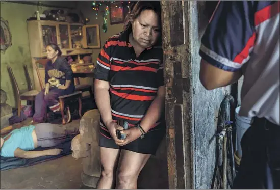  ?? Photograph­s by Marcus Yam Los Angeles Times ?? Georgina Barajas Rios grieves for her mother, Maria Ruiz Olmedo, who died in their home after having symptoms of COVID-19. Paramedic Sergio Garcia is at right.