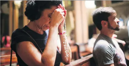  ?? MARIO TAMA/ GETTY IMAGES ?? A woman prays in the Nossa Senhora da Paz church following a Good Friday procession in Rio de Janeiro.