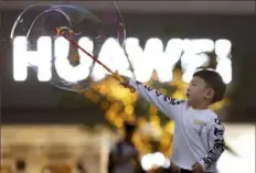  ?? Ng Han Guan/Associated Press ?? A child plays with bubbles Monday near the logo for tech giant Huawei in Beijing. The United States is delaying some restrictio­ns on U.S. technology sales to Huawei.