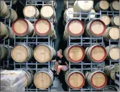  ?? PHOTO: REUTERS ?? Savannah Peterson, a trainee winemaker and daughter of owner Colin Peterson, sits between barrels of wine.