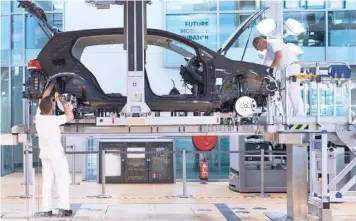  ??  ?? Workers assemble an e-golf electric vehicle at a Volkswagen plant in Dresden, Germany. — Reuters