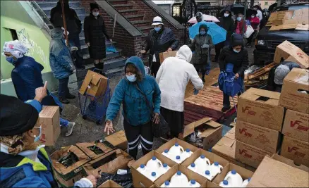  ?? JAMES ESTRIN/ NEW YORK TIMES ?? People receive donated food outside a church in upper Manhattan earlier this month. Economists warn that without more government aid, it will be harder for the unemployed to make rent payments, afford food or keep up with utility bills.